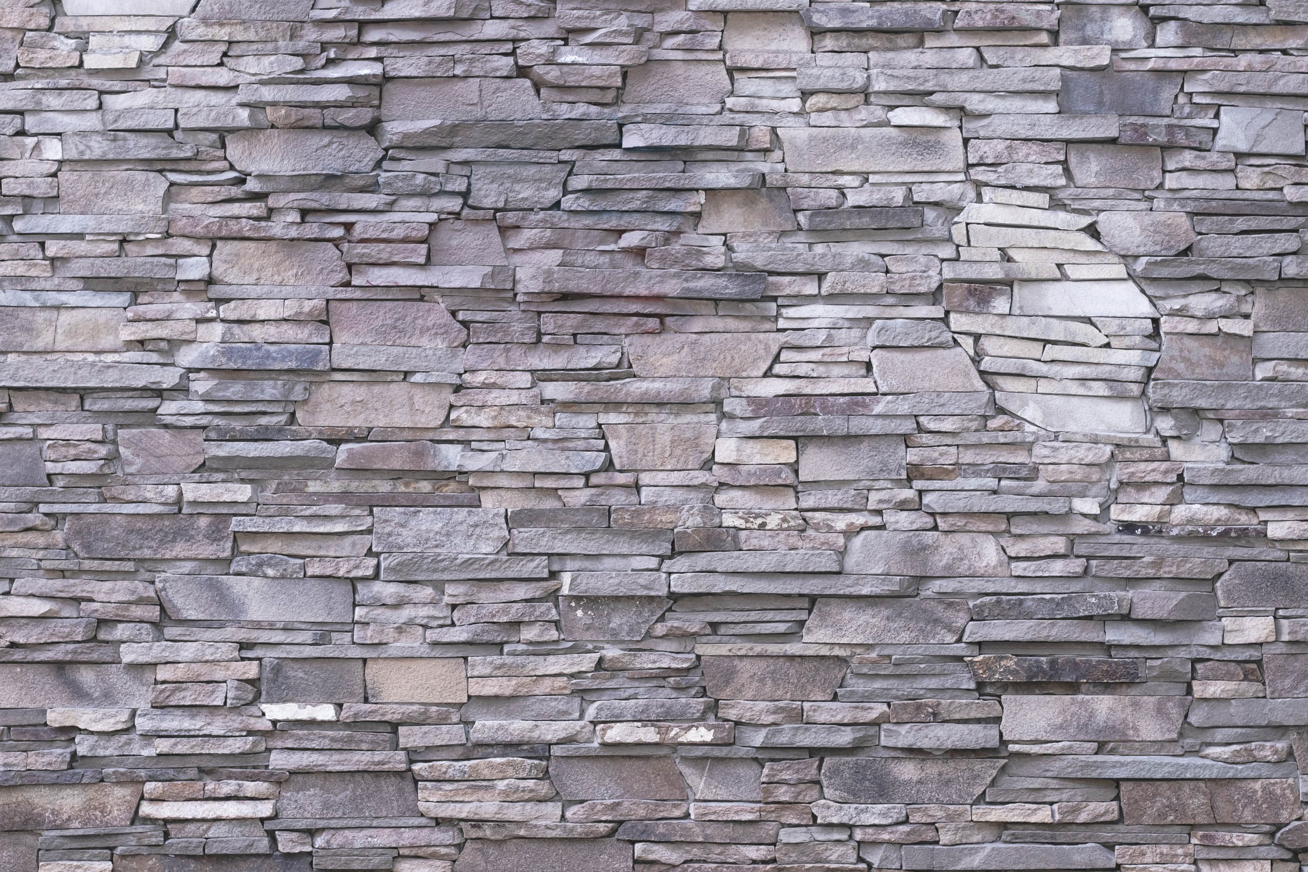 Abstract pattern of gray stone texture. Brick wall background. Rough granite surface. Cracked rock. Decorative tile on facade of building.